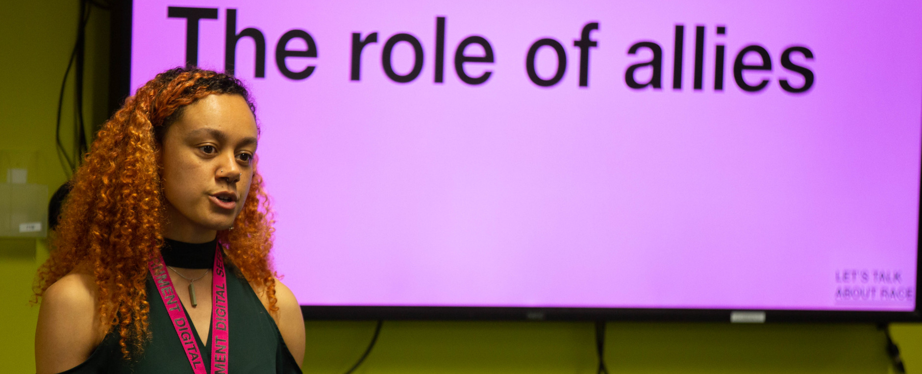 A woman of color with shoulder-length brown hair next to a purple slide that reads, "The Role of Allies".